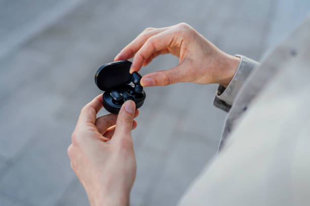 Person holding a pair of wireless earbuds in a charging case, ideal for active lifestyles.